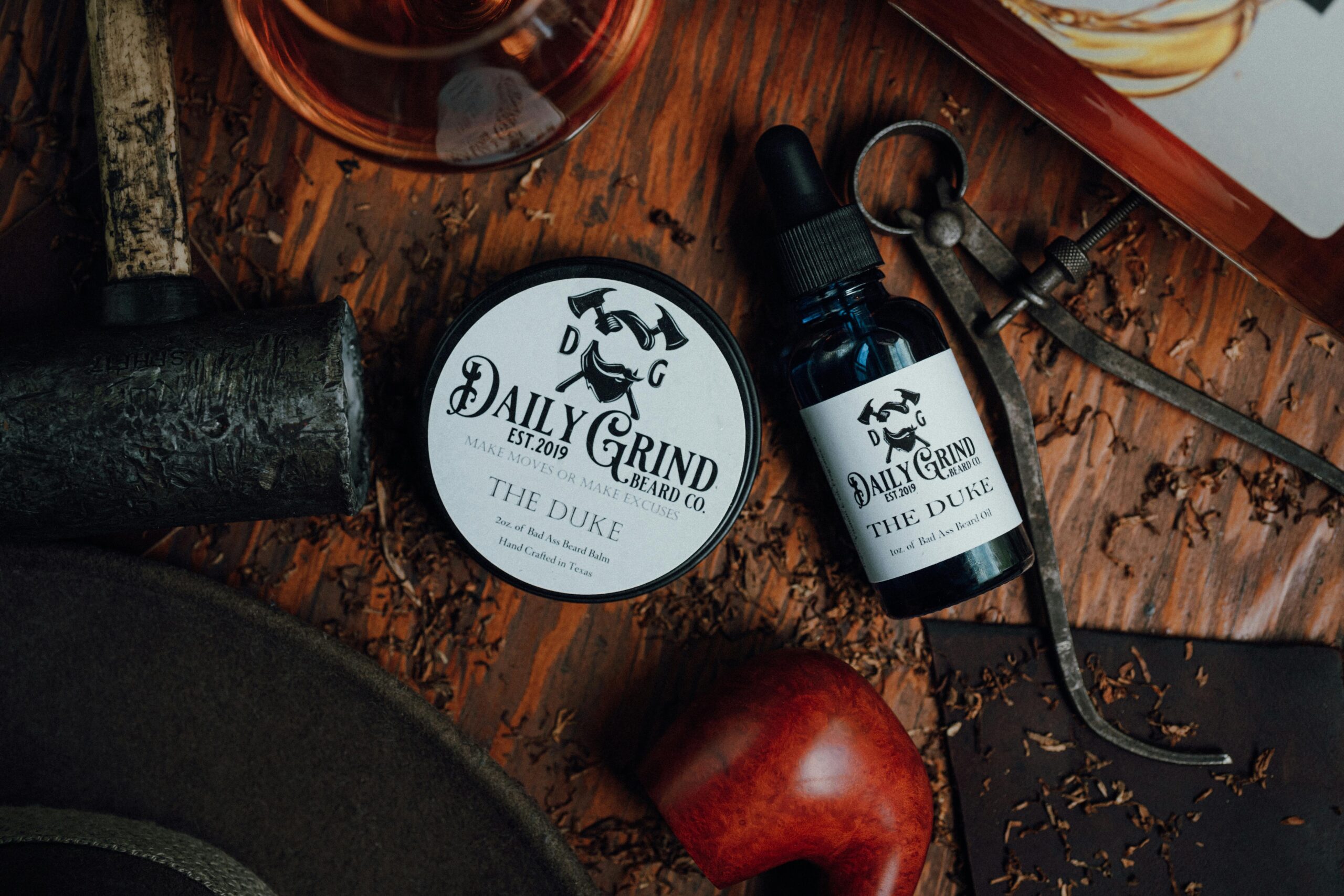 Detailed rustic flat lay of Daily Grind beard balm and oil on wooden surface.